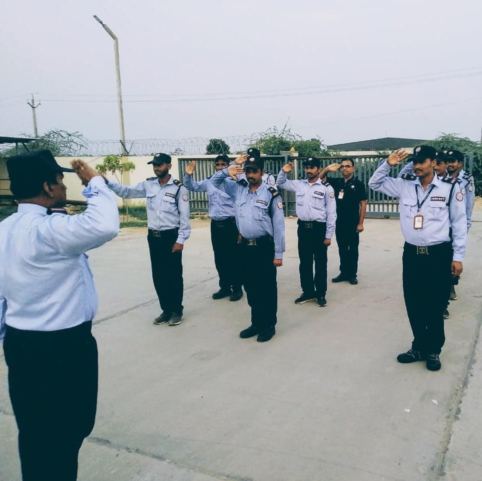 Perfect Group security guards in a saluting drill lineup at a client site gate